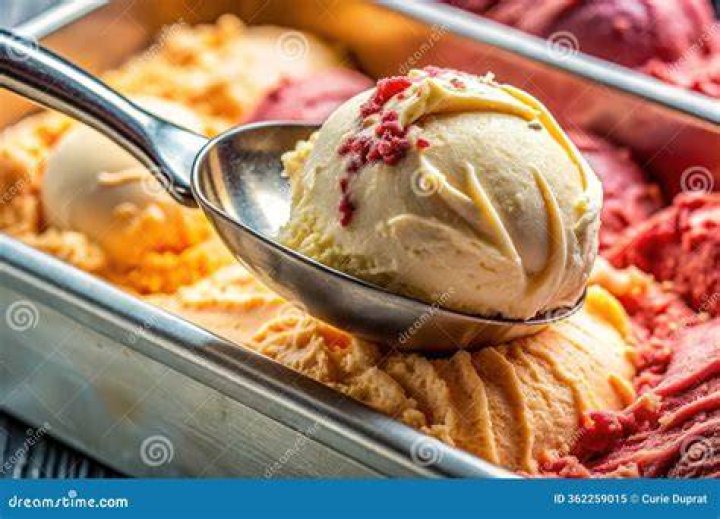 a spoon scooping some food out of a casserole dish with cheese and bacon