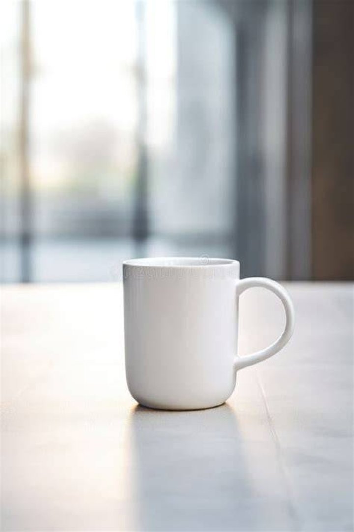 a white coffee cup sitting on top of a blanket